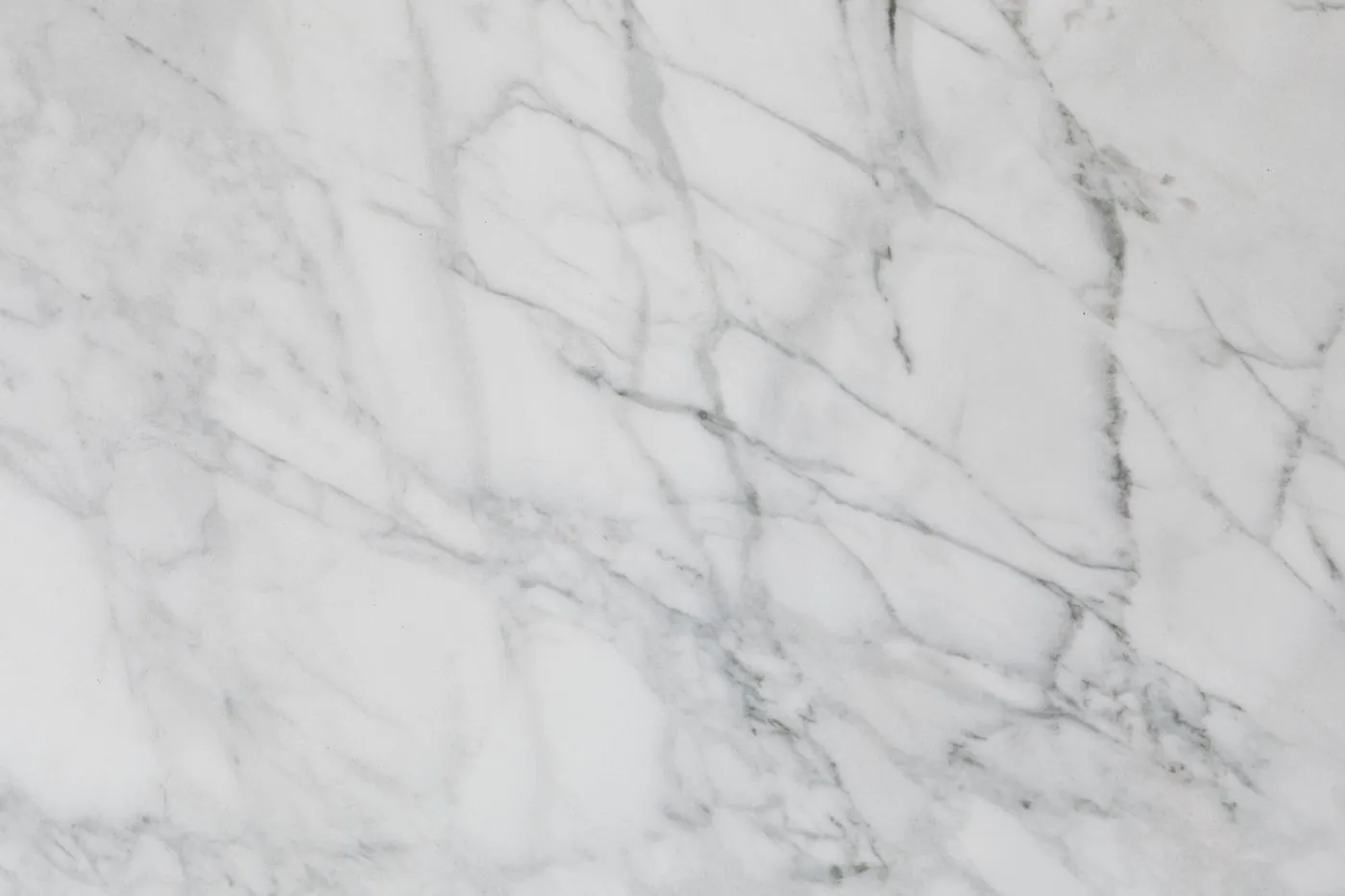 A white marble surface filling the frame, crossed by fine grey veins.
